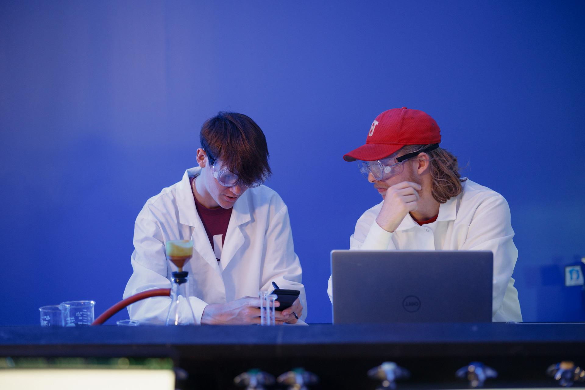 A chemist holding two flasks with chemicals inside of them