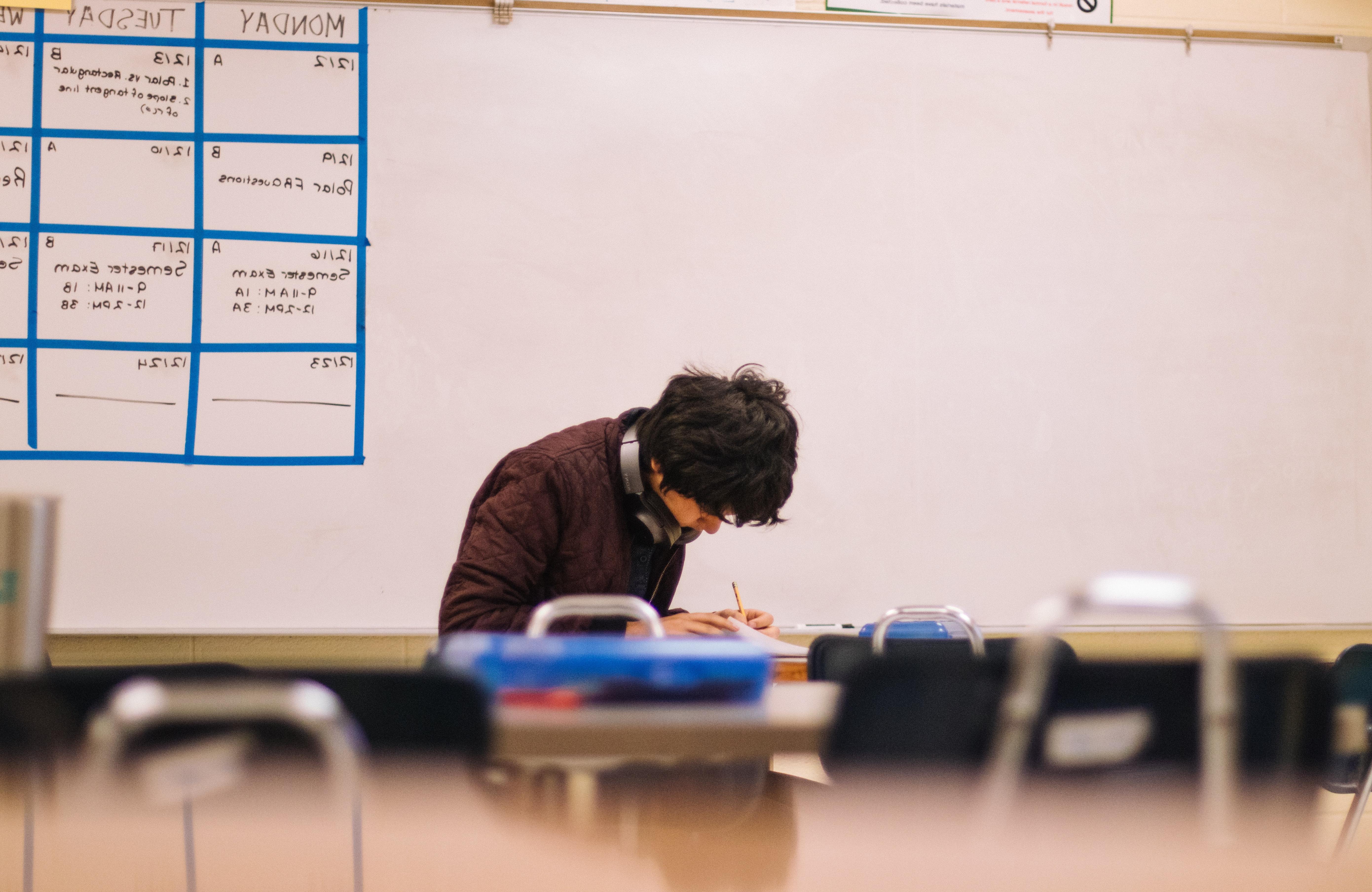 A young man completing homework in a classroom