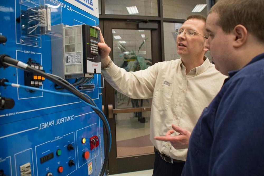 A workforce development professor showing his student how to use a machine